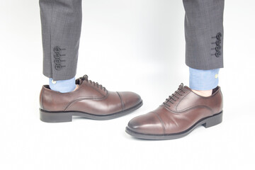Classic brown leather shoes worn on the hands on a white background