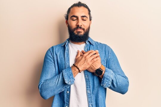 Young arab man wearing casual clothes smiling with hands on chest, eyes closed with grateful gesture on face. health concept.