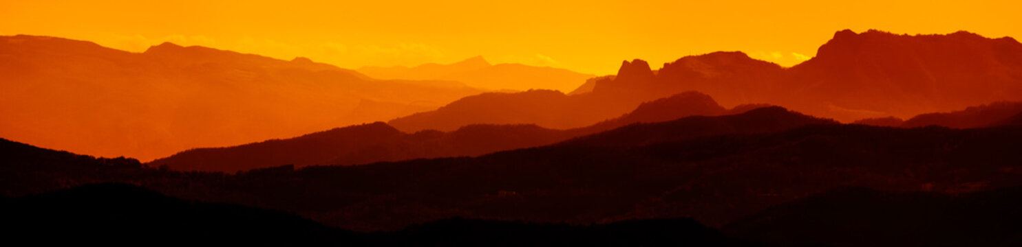 Extra wide panorama of mountain landscape at down. Majestic sunset or sunrise colors over the mountains. Dramatic scene. Beauty world.