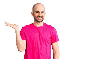 Young handsome man wearing casual t shirt smiling cheerful presenting and pointing with palm of hand looking at the camera.