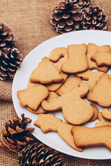Tasty Christmas gingerbread cookies on the white plate on a sackcloth.