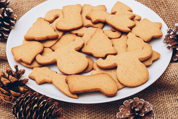 Tasty Christmas gingerbread cookies on the white plate on a sackcloth.