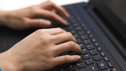 Woman taps on the keyboard of her laptop - close-up - home shooting