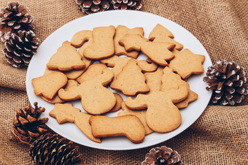 Tasty Christmas gingerbread cookies on the white plate on a sackcloth.