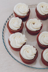 Delicious chocolate cupcakes with swirled frosting cream on top on the bright tablecloth.