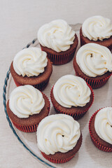 Delicious chocolate cupcakes with swirled frosting cream on top on the bright tablecloth.