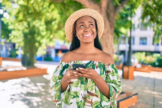 Young african american tourist woman on vacation smiling happy using smartphone at the city.