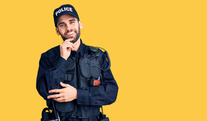 Young handsome man with beard wearing police uniform looking confident at the camera with smile with crossed arms and hand raised on chin. thinking positive.