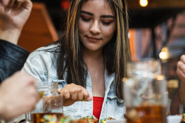 Latin woman placing sauce on her tacos