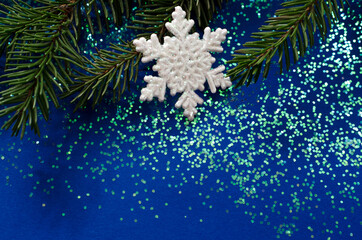 Fir branch and snowflake on a bright blue background.