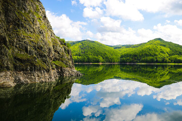 Nice view of the mountains and green hills. Reflection of hills in a lake.