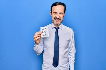 Middle age business man asking for social rights holding paper with we are equal message looking positive and happy standing and smiling with a confident smile showing teeth