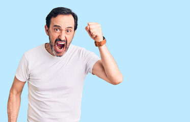 Naklejka premium Middle age handsome man wearing casual t-shirt angry and mad raising fist frustrated and furious while shouting with anger. rage and aggressive concept.