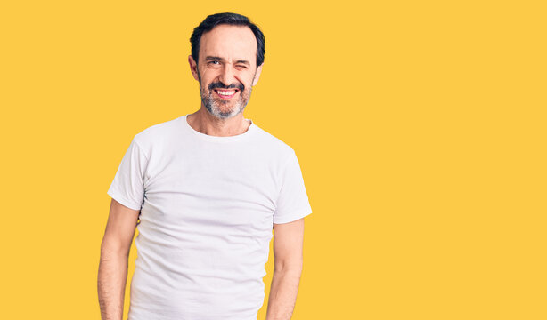 Middle age handsome man wearing casual t-shirt winking looking at the camera with sexy expression, cheerful and happy face.