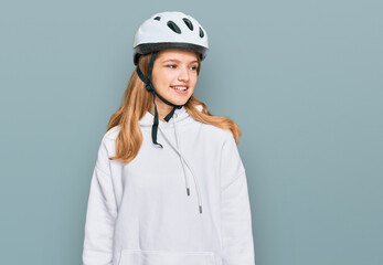 Beautiful young caucasian girl wearing bike helmet looking away to side with smile on face, natural expression. laughing confident.
