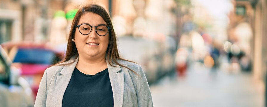 Young hispanic plus size businesswoman smiling happy standing at the city.