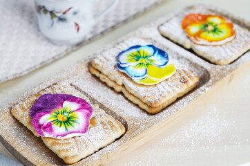 Cookies decorated with colorful sugar flowers and powdered sugar. Selective focus