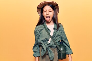 Fototapeta premium Beautiful child girl wearing explorer hat sticking tongue out happy with funny expression. emotion concept.