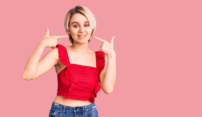 Young beautiful blonde woman wearing casual clothes smiling cheerful showing and pointing with...