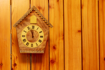 Cuckoo clock with Roman numerals on a wooden wall. Place for your text.