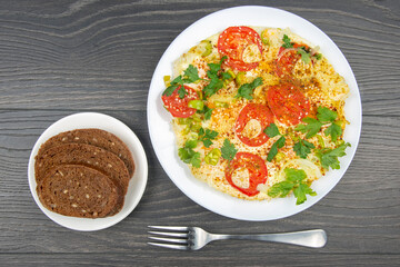 cooked fried omelet with herbs and vegetables in a white plate on a wooden table