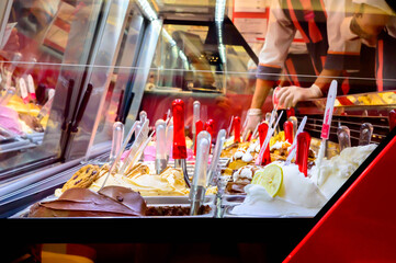 Serving pulled in an ice cream parlor. Many different colored ice cream flavors.
