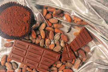 Premium chocolate concept. Cocoa beans, powder and chocolate bar on a silver background.