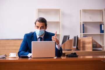 Young male employee working in the office wearing mask