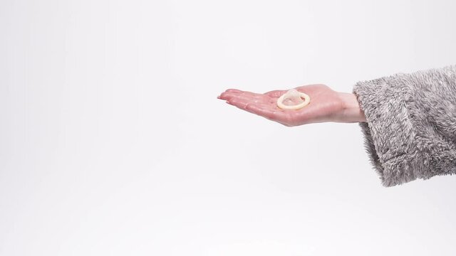 Condom. A female hand shows a rubber condom.