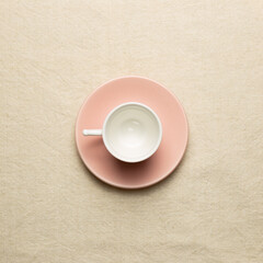 Pink coffee cup on beige fabric background. top view