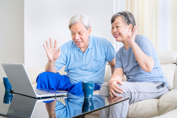 Old couple doing a video call with laptop at home