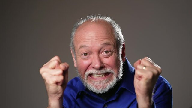 Portrait of cheerful man with beard dancing looking at camera and yelling and laughing on grey background. Good looking caucasian man team leader in modern office. Concept of people and emotions