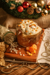 White chocolate panettone with dried apricot on wooden table with christmas ornaments