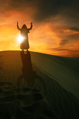 Silhouette of Arabian man praying on sand dunes