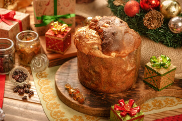 Panettone, raisins and candied fruit cubes on wooden cutting board with christmas ornaments