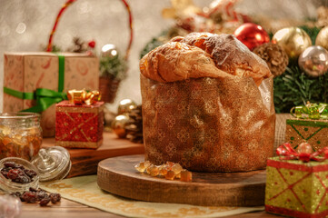 Panettone, raisins and candied fruit cubes on wooden cutting board with christmas ornaments