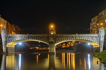 Historical bridge over a river with city lights on a monument at night