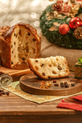 A slice of panettone and candied fruit cubes on wooden cutting board with christmas ornaments