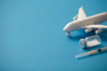 vaccine canister with syringe and white plane, blue background