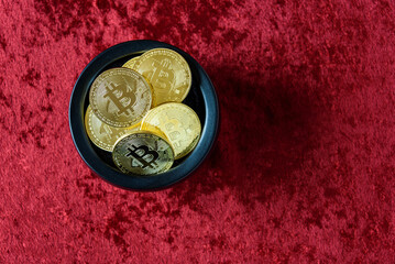 Gold bitcoins in a black pot on a red background
