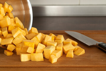 Bowl with dices pumpkin and knife on wooden board