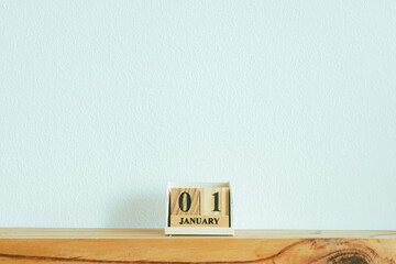 Wooden pieces with text 01 JANUARY on white wall in concept of new year.