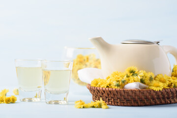 Hot chrysanthemum tea drink in glass cup with fresh flower on light blue background