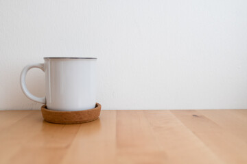 White hot coffee cup on wooden table and white wall with copy space.