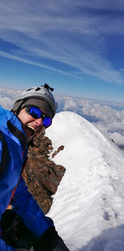 Alpinista che urla e sorride felice ed euforico in cima alla montagna con neve e cielo blu assolato nelle alpi-Monte Rosa
