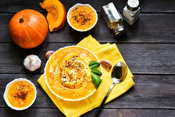 Pumpkin soup with spices and garlic, yellow napkin on a wooden background. copy space, flat lay.
