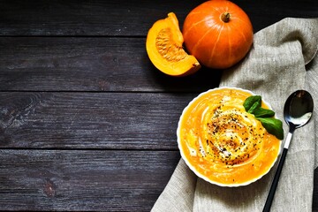 Pumpkin soup with napkin on a wooden background. Healthy food concept. Copy space, flat lay. Thanksgiving.