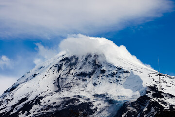 Top of the Lanin Volcano from Lake Tromen in Neuquen, Argentina. This volcano is covered by eternal snow and with some clouds that surround the caldera of the volcano.