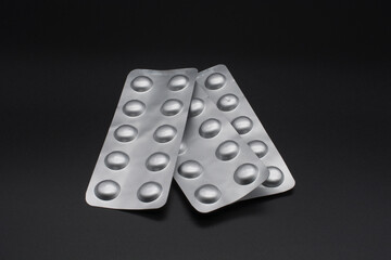Metallic cartons of medicine pills. Black background.