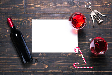 Bottle and glasses of red wine, Christmas ornaments and fir tree branches on wooden dark table. Template paper for notes